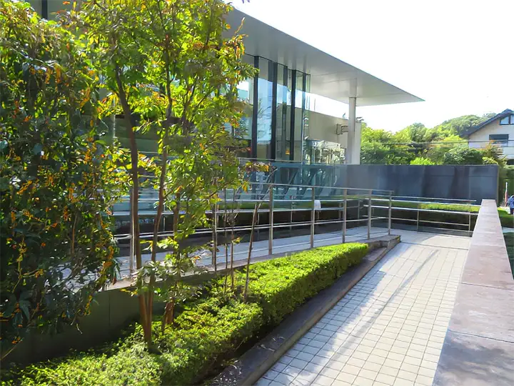 両側に手すりが設置された、建物の入り口へと続く緩やかな舗装スロープ