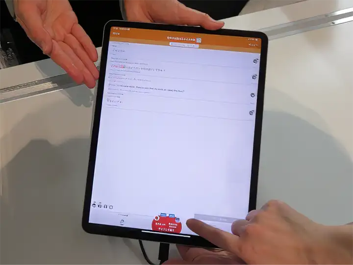 スタッフが提示している、タブレット端末上のUDトークの翻訳・音声認識画面