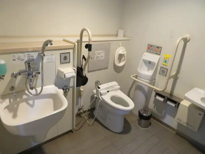 オストメイト対応の汚物流し、手すり付き便器、洗面台がゆったりと配置されたトイレ内部