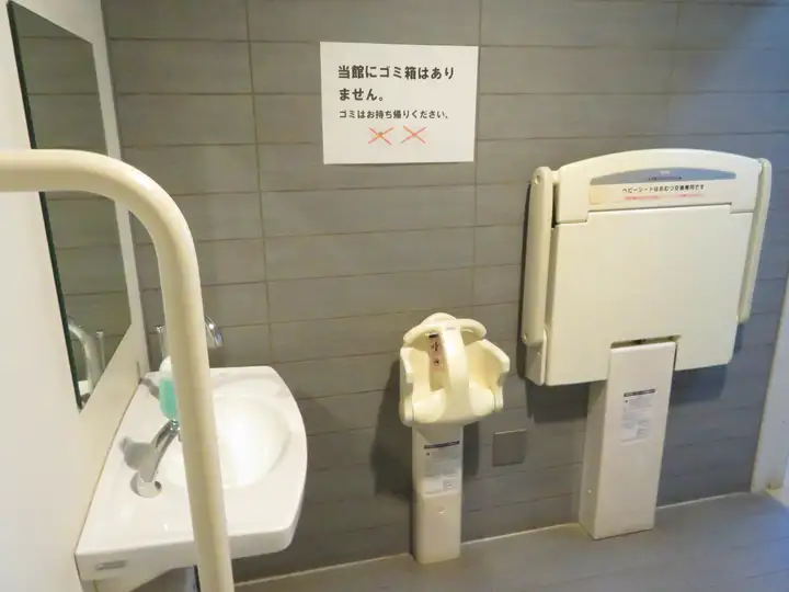 壁面に設置された開閉式のベビーシート（おむつ交換台）と幼児用ベビーチェア