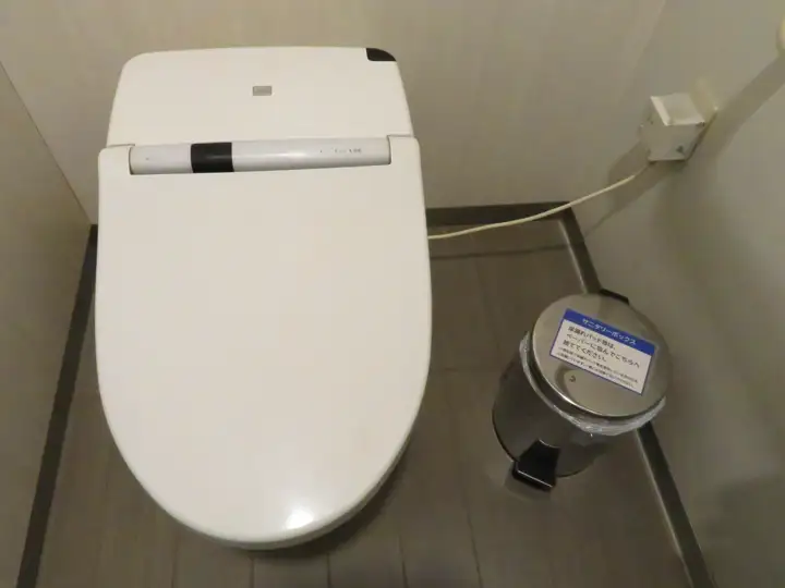 洋式トイレの便器横に設置された、足踏みペダル式のステンレス製サニタリーボックス
