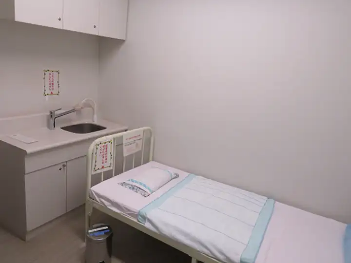 手洗い用の流し台と、シーツと枕が用意されたベッドが設置された授乳室の内部