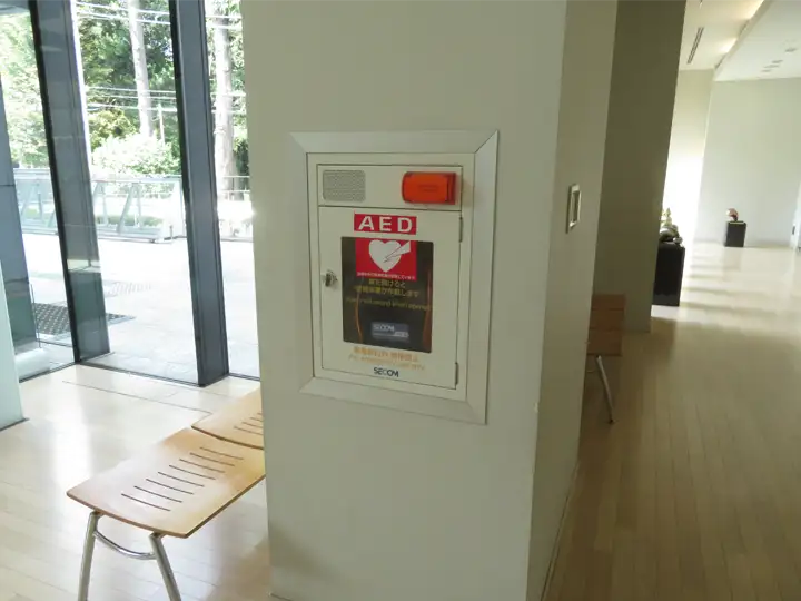 施設1階の通路にある白い柱に埋め込まれるように設置された、赤いランプが目印のAED収納ボックス
