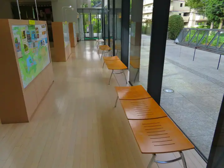 施設内の通路に設置された、木製の座面と金属製の脚を持つベンチ