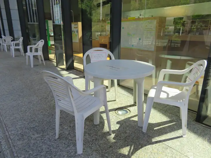 屋外のウッドデッキスペースに設置された、円形のパラソル付きテーブルと椅子のセット